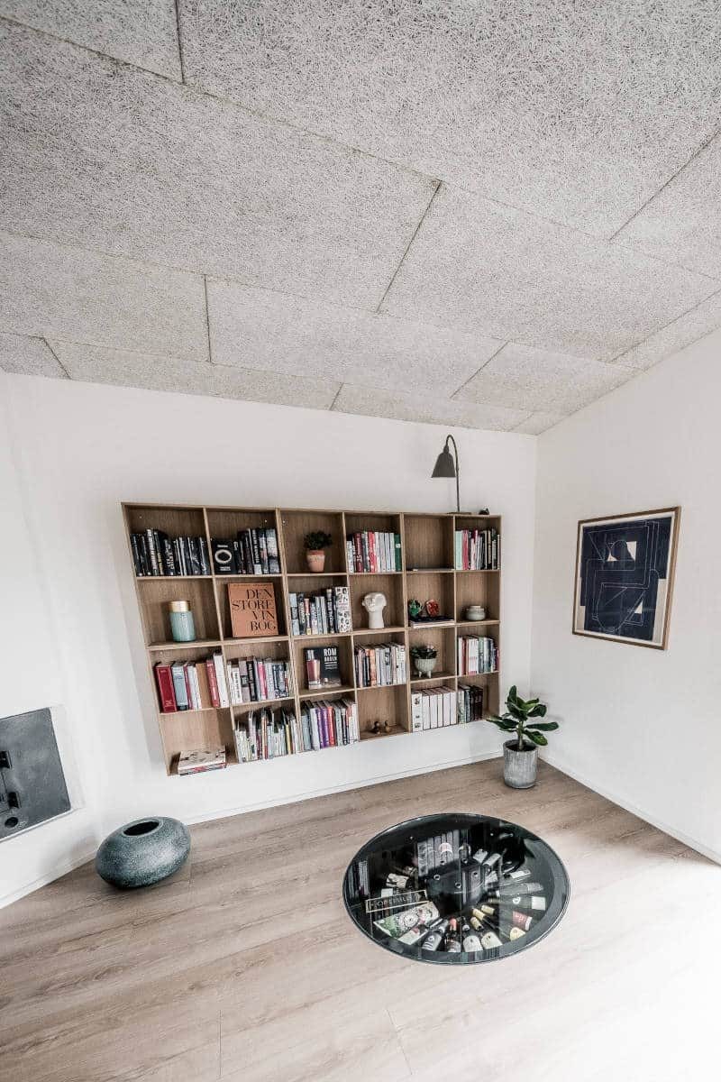 Stue med reol og et rundt glas i gulvet.